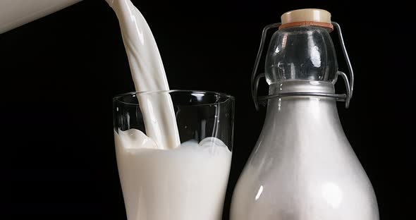 900372 Milk being poured into Glass against black Background, Slow Motion 4K alt