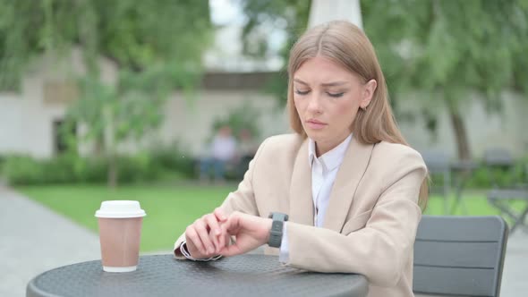 Young Businesswoman with Coffee Waiting Checking Time in Outdoor Cafe alt
