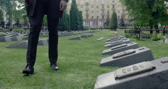 Sad Young Man in Suit Stands on the Grave of the City Cemetery
