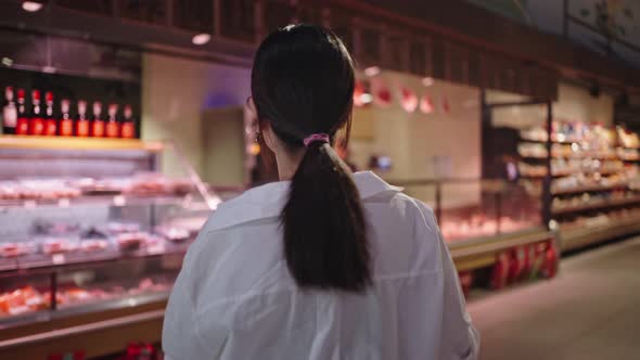 Young Woman Walks About Supermarket Searching Products alt
