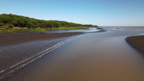 Low aerial pan of brown sand banks and swamp by Rio de la Plata coast alt