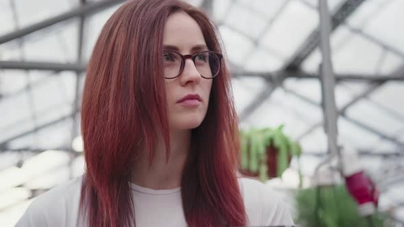 Female Scientist in a Greenhouse on the Background of the Glass Roof