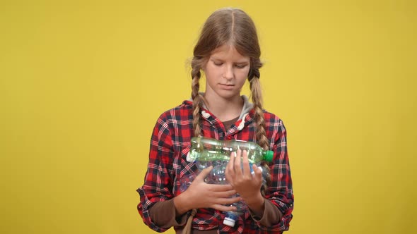Concentrated Serious Teenage Girl Looking at Camera Holding Used Plastic Bottles alt