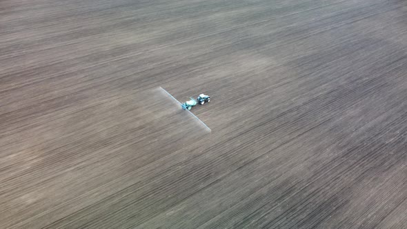 Aerial view tractor spraying seeds on land field