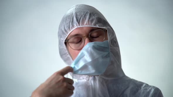 A Person in a Protective Suit, Removes the Medical Mask and Breathes Fresh Air Without Viruses. The