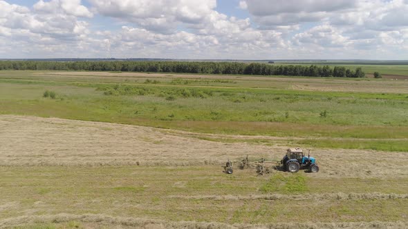 Tractor with Rake Tedders on the Farm Field alt