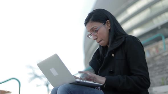 Smiling Hindu Woman in Eyeglasses Typing on Laptop Outdoor alt