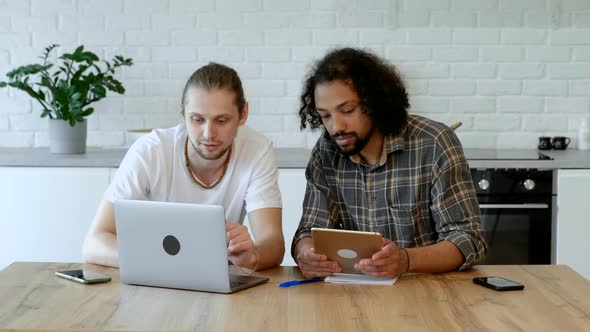 Two Young Male Freelancers Are Working At Home on an Online Project