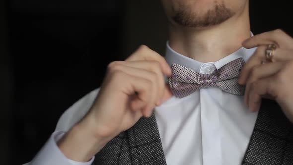 A Man Dresses and Straightens a Bow Tie