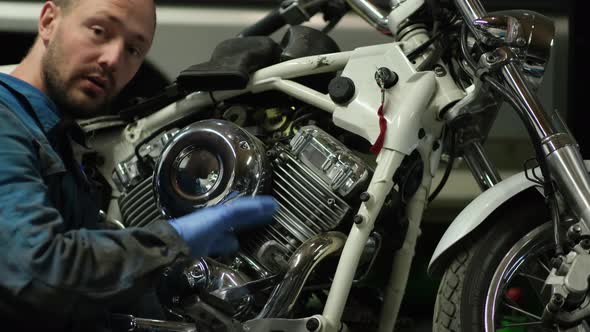 guy mechanic in blue overalls next to a motorcycle