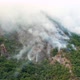 Rainforest burning in a WILDFIRE, white plumes of thick smoke billowing over green hillside - cliff. - VideoHive Item for Sale