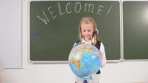 School Girl with Globe in Classroom Chalkboard on Background alt