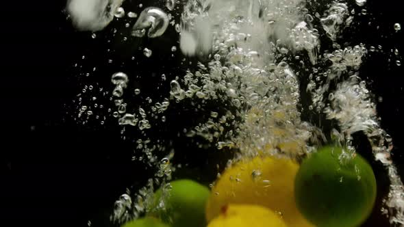 Closeup of Falling Ripe Lemons Oranges and Limes Into Sparkling Water on Black Background Making alt