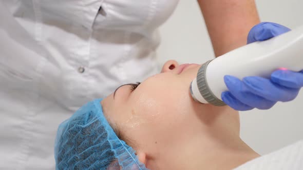 Non-surgical Face Lifting in Beauty Clinic. Cosmetologist Moves Manipulator on Client Face alt