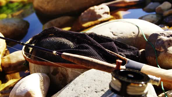 Fly fishing rod, reel and tackle box on rock alt