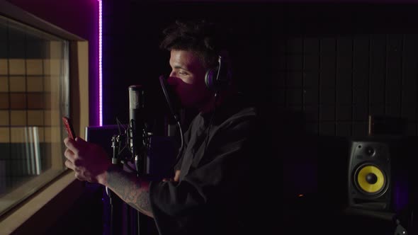 Charismatic Cool African American Rapper with Smartphone in Headphones Recording Track in Studio alt
