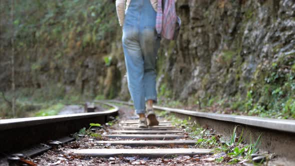 Young Backpacker Woman is Walking on Train Rail Alone Rear View