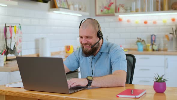 Cheerful Mature Man Emotionally Playing a Game on His Phone During Work Break While Sitting at His alt