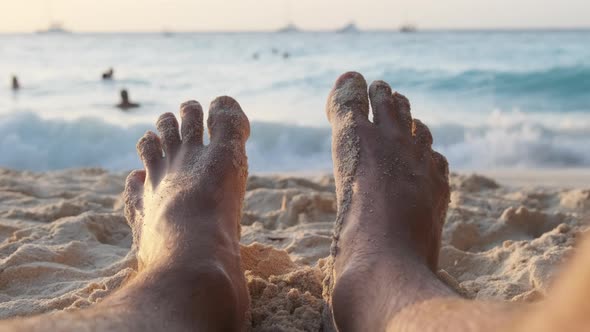 POV Feet of Young Man Lying on Sandy Beach By the Ocean During Sunset Zanzibar alt