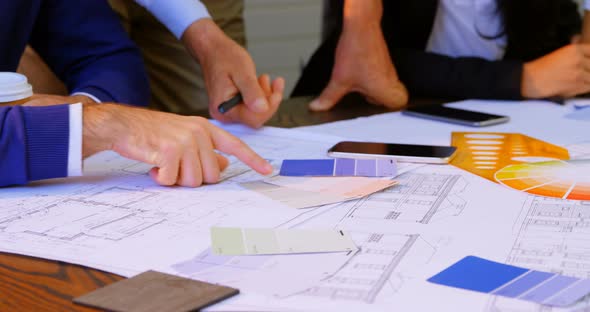 Executives discussing over blueprint in conference room at office 4k alt