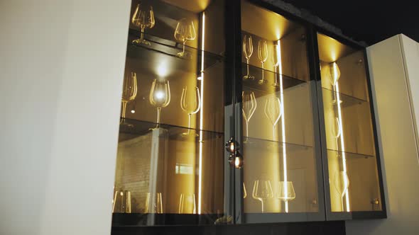 Black Cupboard with Glass Wall in the Kitchen with Crockery and Clear Glasses with Lighting alt