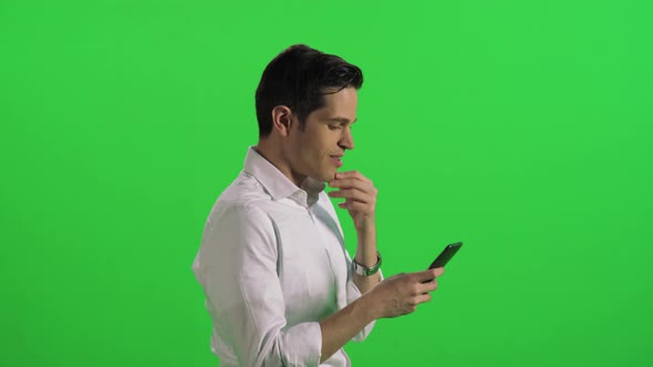 A Young Businessman Walking in A Medium Shot, Relaxed, Texting or Using an App alt