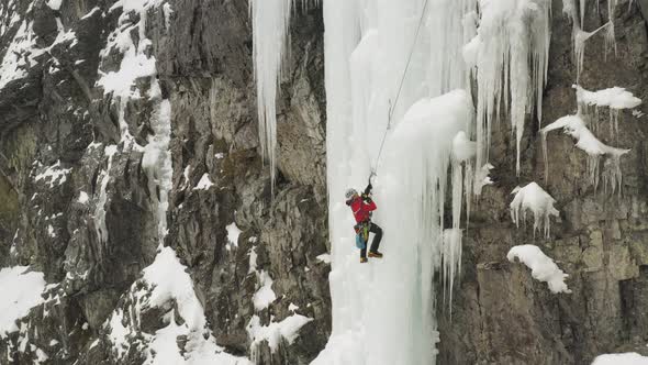 Lone ice climber shakes off ice from axe climbing cascade Maineline, Mount Kineo alt