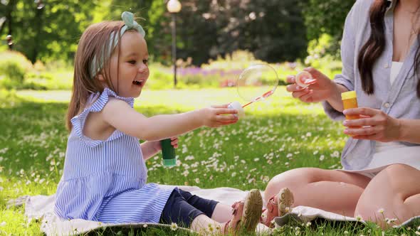 Mother with Daughter Blowing Soap Bubbles at Park