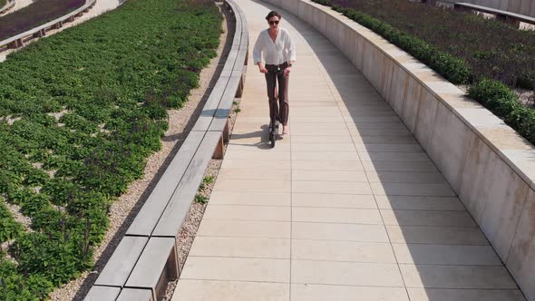 Eco-friendly Mode of Transport - Aerial View of a Woman in a White Blouse and Trousers, Going To a alt