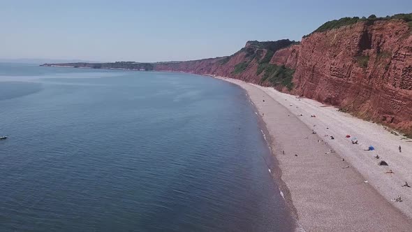 Aerial, flying over the ocean alongside red cliffs in Budleigh Salterton, Jurassic Coast, STATIC CRO alt