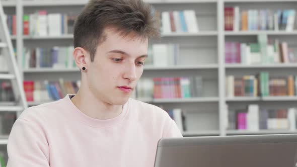 Cropped Shot of a Young Male Student Smiling To the Camera at the Library