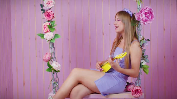 Sexy Blonde Girl Sit on Swing with Ukulele Sings alt