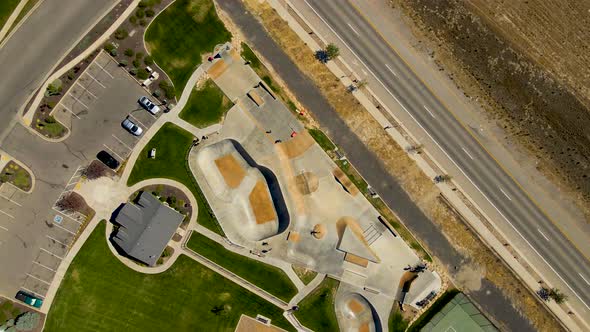 Dizzying aerial spinning view of an urban skate park full of kids having fun in summer alt