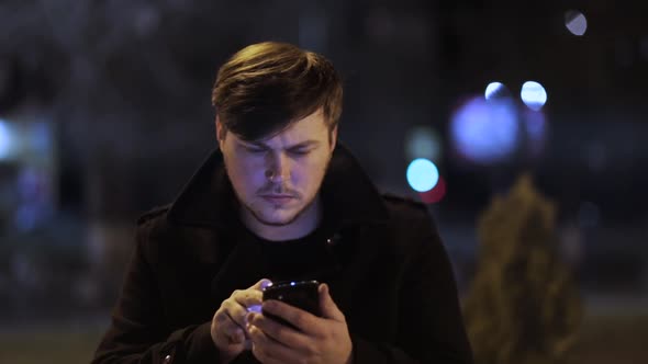 Close-up of a man typing a message on smartphones outdoors.