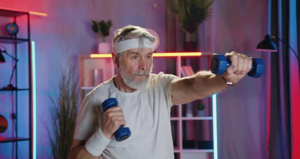 Senior Man in Sportswear Doing Boxing Exercises with Dumbbells alt
