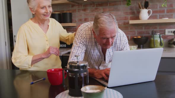 Senior Caucasian couple happily working together on a laptop at home alt