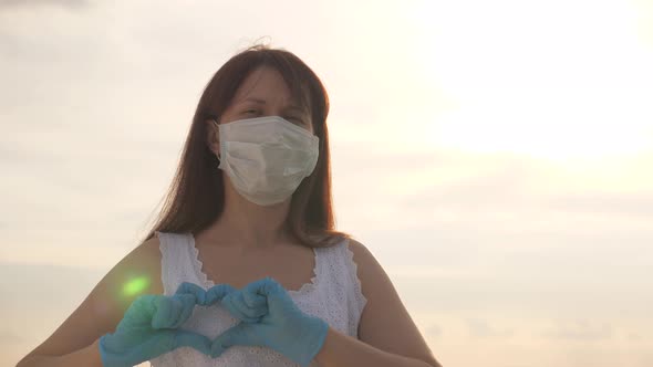 Female Doctor Showing Fingers of Heart and Love for Patients. Girl in a Protective Mask and Medical
