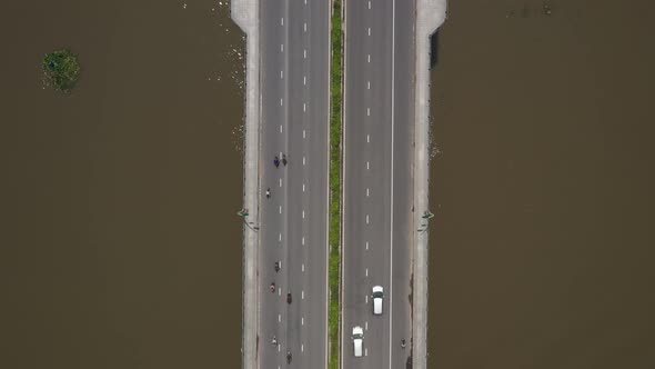 Top down view of modern bridge across a river. Cars, Trucks and motorscooter traffic passes across t alt