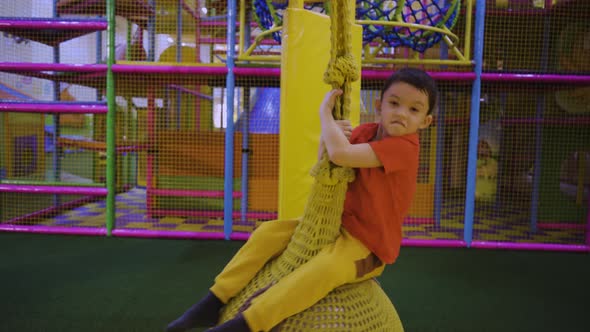 A Little Boy Swings on a Hanging Ball at a Leisure Centre