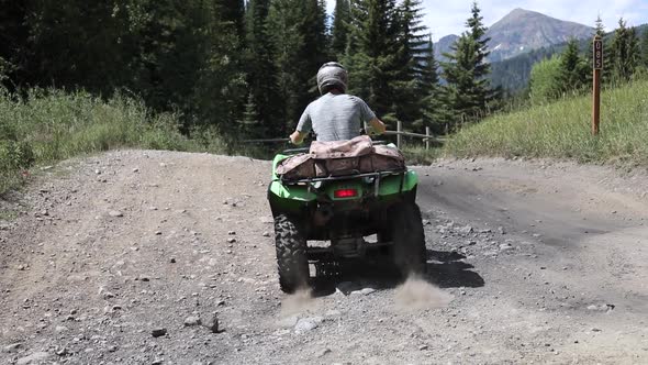 Shot of an ATV Rider driving his quad on a dirt path in the Wasatch Mountains. alt