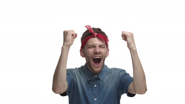 Successful Handsome Guy with Beard Wearing Red Hiphop Headband Winning Something Raising Hands Up in