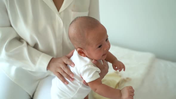 Mother Patting on Back of Asian Baby alt
