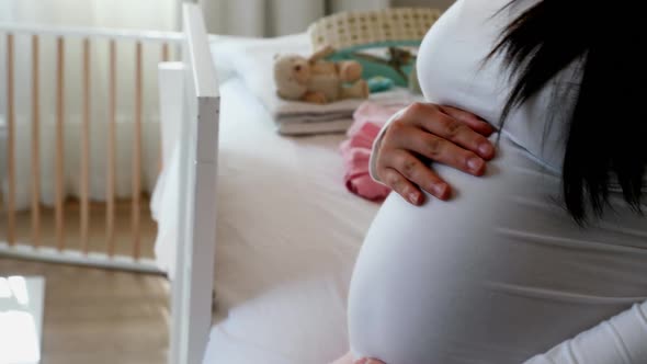 Man making cot with pregnant woman in bedroom alt