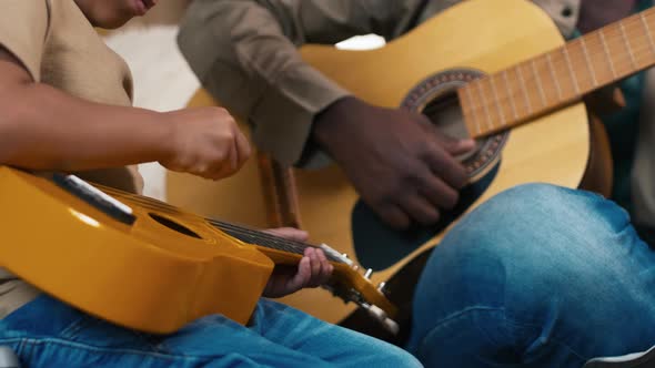 Child imitating playing guitar as his father near him