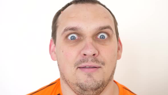 Closeup Face a Surprised Emotional Man with Blue Eyes Looking Into the Camera on a White Background