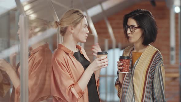 Two Female Colleagues Chatting over Coffee in Office alt