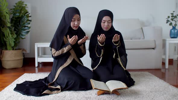 Young Muslim woman and female friend reading Quran and praying alt