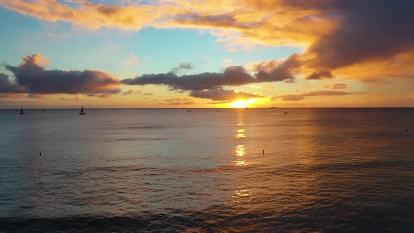 Aerial Drone Flying Over Beautiful Ocean Sunset with Sailboats on Waikiki Beach in Honolulu, Hawaii alt