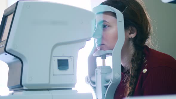 A Lady is Having Her Eyes Examined By a Medical Device alt
