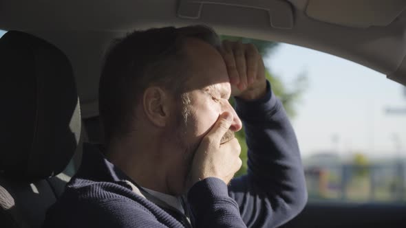 A Middleaged Handsome Caucasian Man Yawns and Acts Tired in a Car  Side Closeup